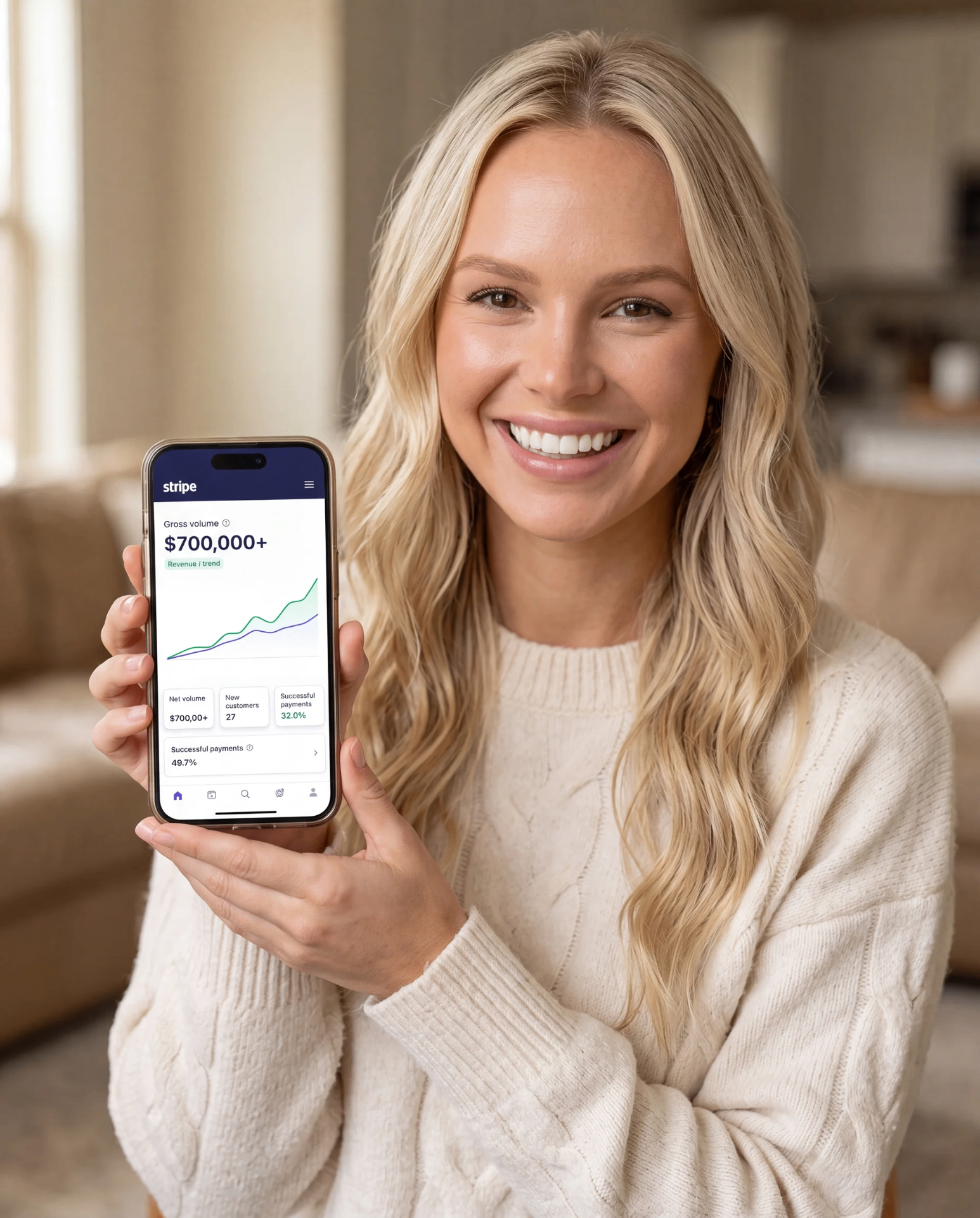 Katie holding a phone showing $700,000+ in Stripe revenue